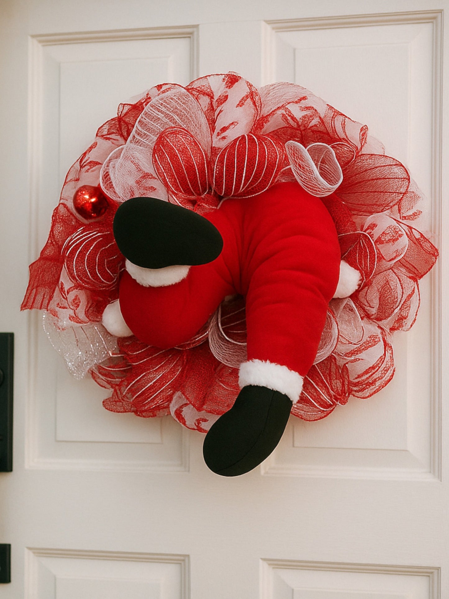 Decorative wreath with a red and white design on a white door
