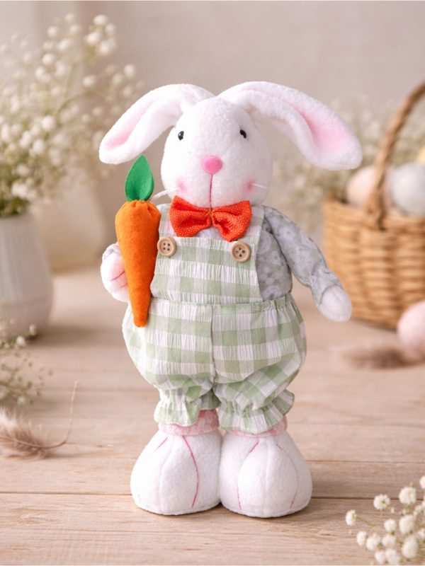Plush toy rabbit in overalls holding a carrot on a wooden surface with a blurred background